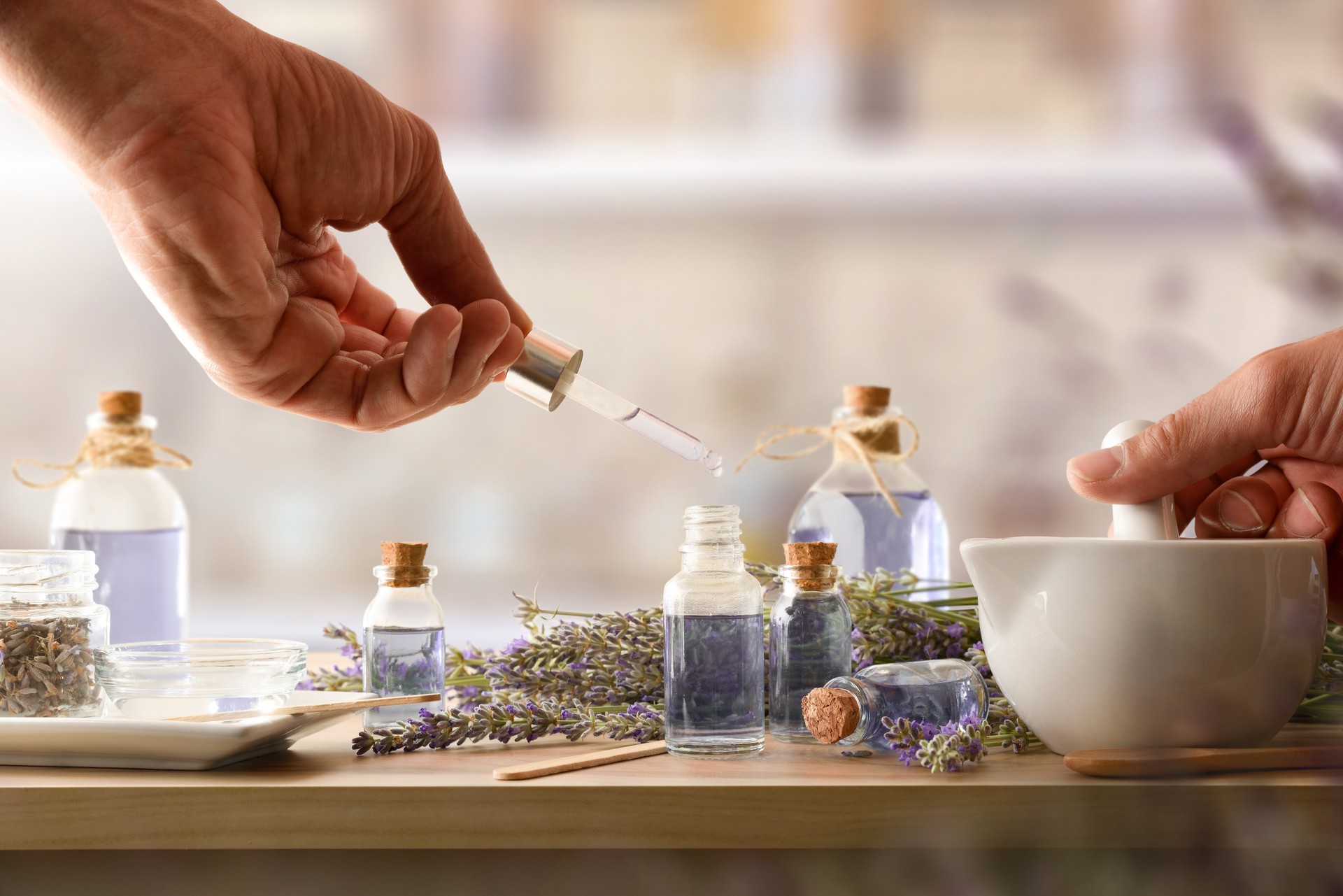 Person making homemade lavender essence with tools on wooden bench